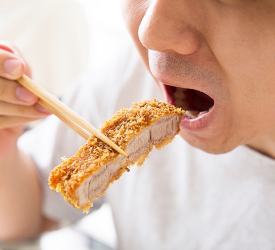 カツを食べる男性